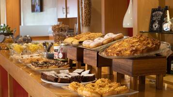Een ontbijtbuffet met diverse gebakken producten, zoals gebakjes, donuts en brownies.
