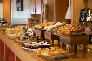 Un bufé con diversas opciones de repostería, como pasteles, rosquillas y brownies.