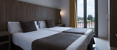 Une chambre d’hôtel avec deux lits, une tête de lit en bois, des tables de chevet et un balcon avec vue.