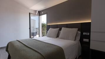 A modern bedroom with a large bed, a green throw blanket, and a view of a balcony.