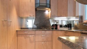 Een moderne keuken met houten kastjes, een granieten aanrecht en een roestvrijstalen afzuigkap.