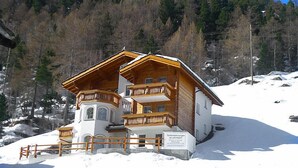 Een chalet met een houten balkon en een besneeerd landschap.