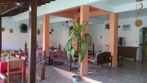A spacious indoor area with a dining setup, a large potted plant, and a reception desk. - Pousada Caminho de Pedras (Cairu)