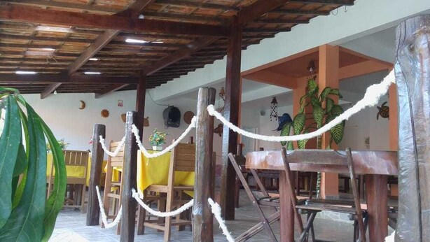 A rustic wooden structure with a thatched roof, surrounded by wooden furniture and plants. - Pousada Caminho de Pedras (Cairu)