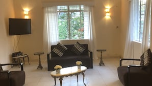 A living room with a sofa, two armchairs, a coffee table, and a TV mounted on the wall. - Lac s Villa (Freetown)