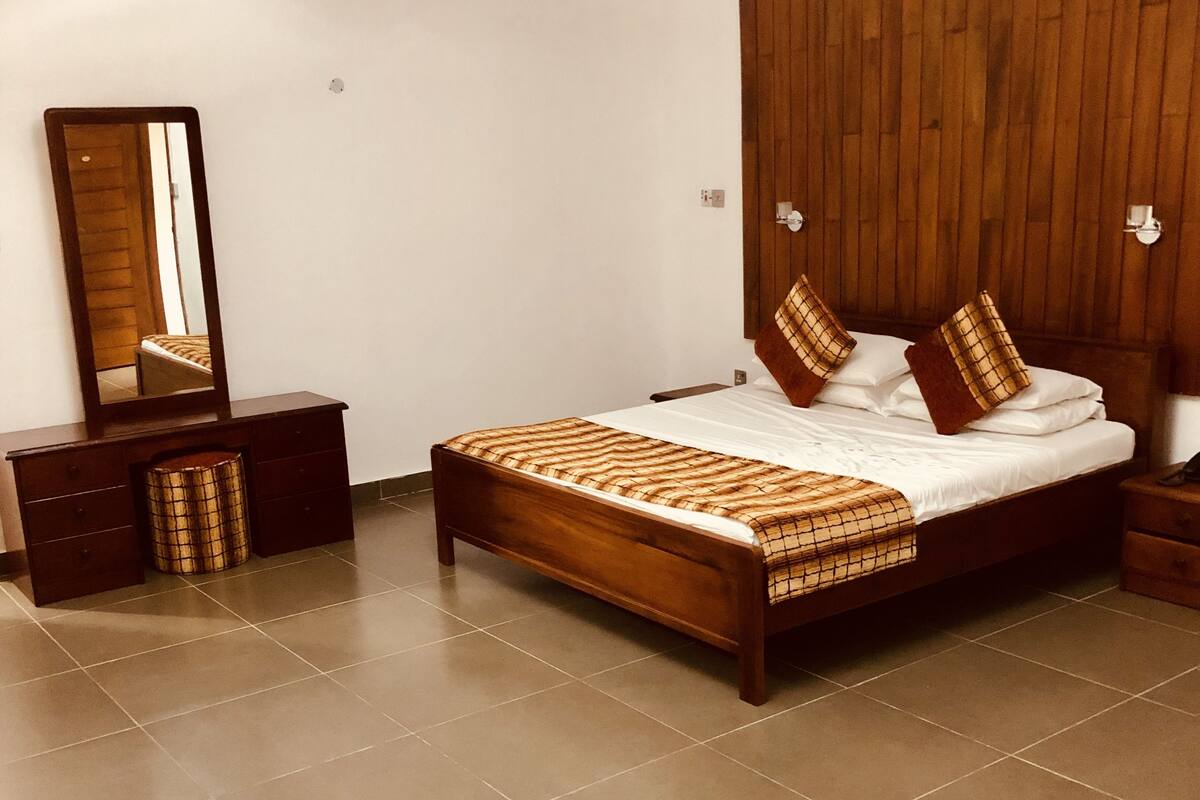 A bedroom with a wooden bed, a nightstand, a dresser, and a mirror.