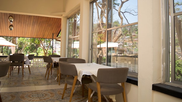 An indoor dining area with large windows, wooden ceiling, and patterned floor tiles. - Lac s Villa (Freetown)
