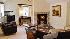A cozy living room with a stone fireplace, leather sofa, and a television.