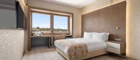 Una habitación de hotel moderna con una cama grande, un escritorio y vistas al campo.