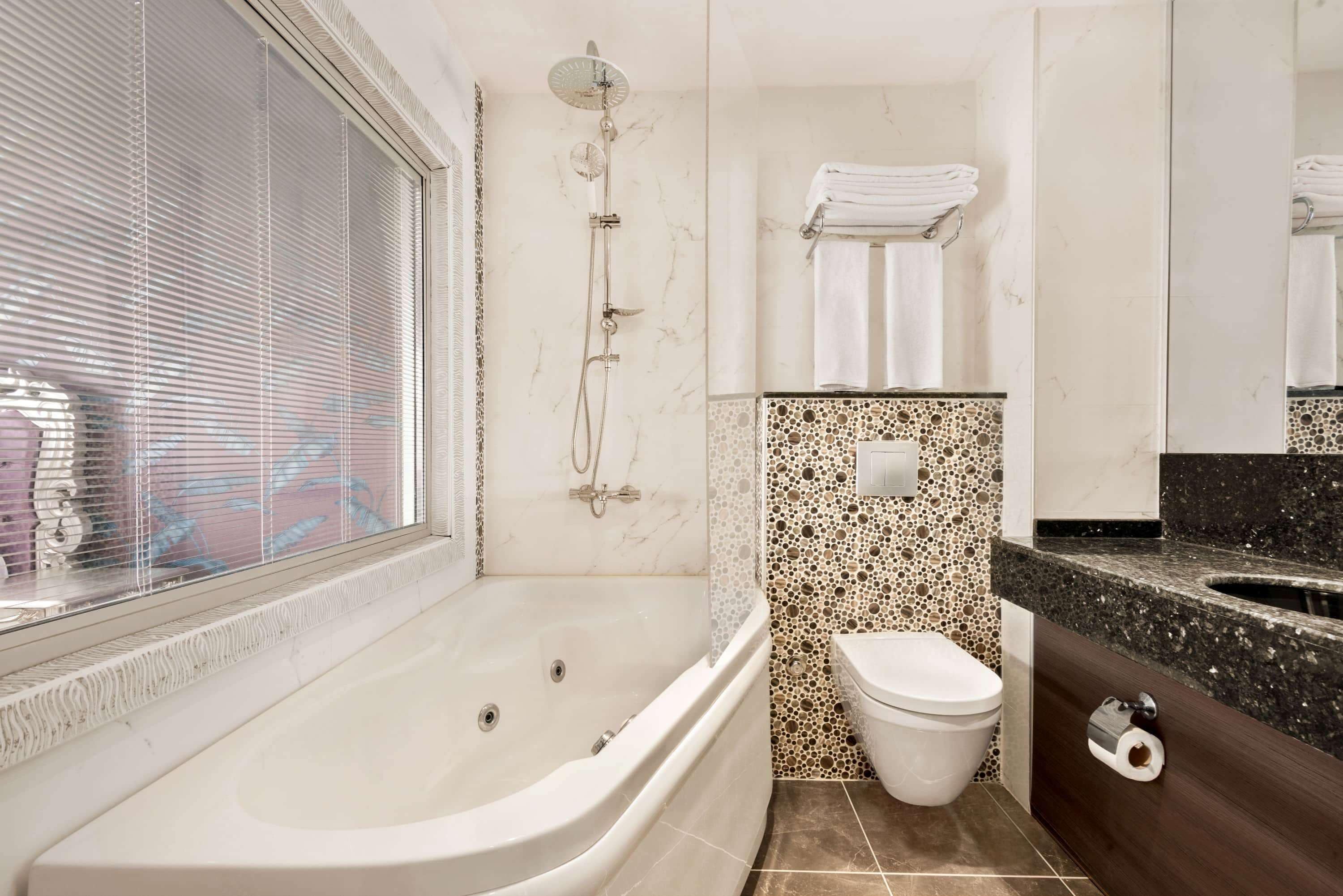 A bathroom with a large bathtub, a shower, a toilet, and a sink.