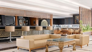 A modern lobby with a sofa, armchairs, a coffee table, a bar area, and decorative screens.