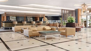 A spacious lobby with a modern bar area, comfortable seating, and a large decorative plant.