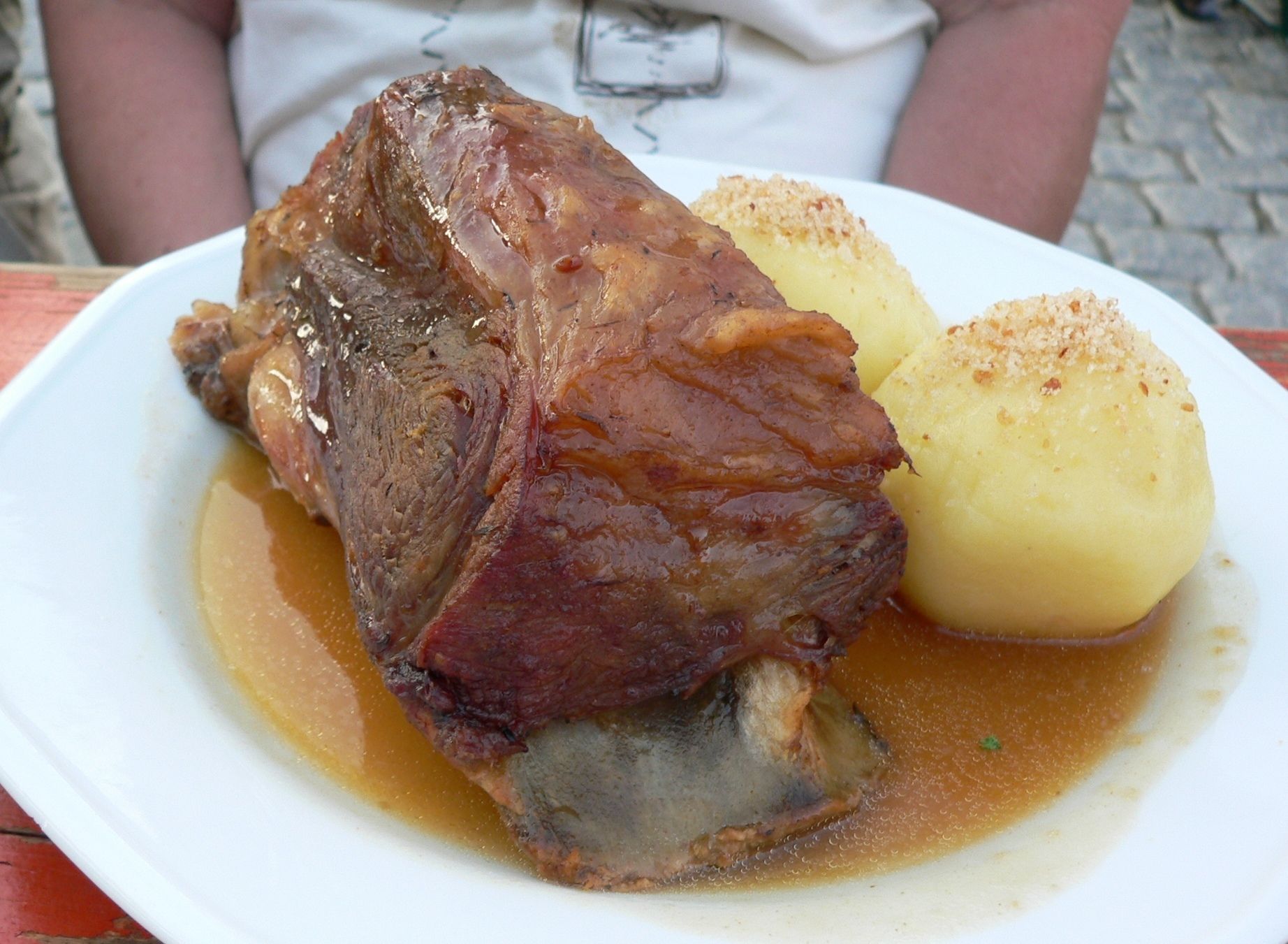 A plate with a large piece of meat and a boiled potato.