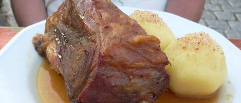 A plate with a large piece of meat and a boiled potato.