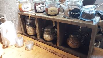 Een houten plank met meerdere glazen potten, voorzien van etiketten met inhoud zoals abrikozen, chocolade en koffie.