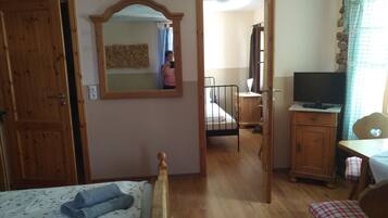 A bedroom with a wooden bed, a bedside table, a mirror, a wardrobe, and a television.