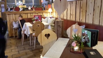 Interior acogedor de un restaurante con mobiliario de madera, una zona de bar y una mesa con una vela y un marco de fotos.