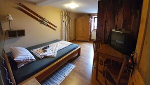 A room with a bed, a television, a wooden wardrobe, and a window.