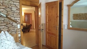 A bedroom with a bed, a wooden door, a stone wall, and a mirror.