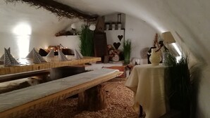 A cozy, rustic interior with wooden benches, a table with a white tablecloth, and a fireplace.