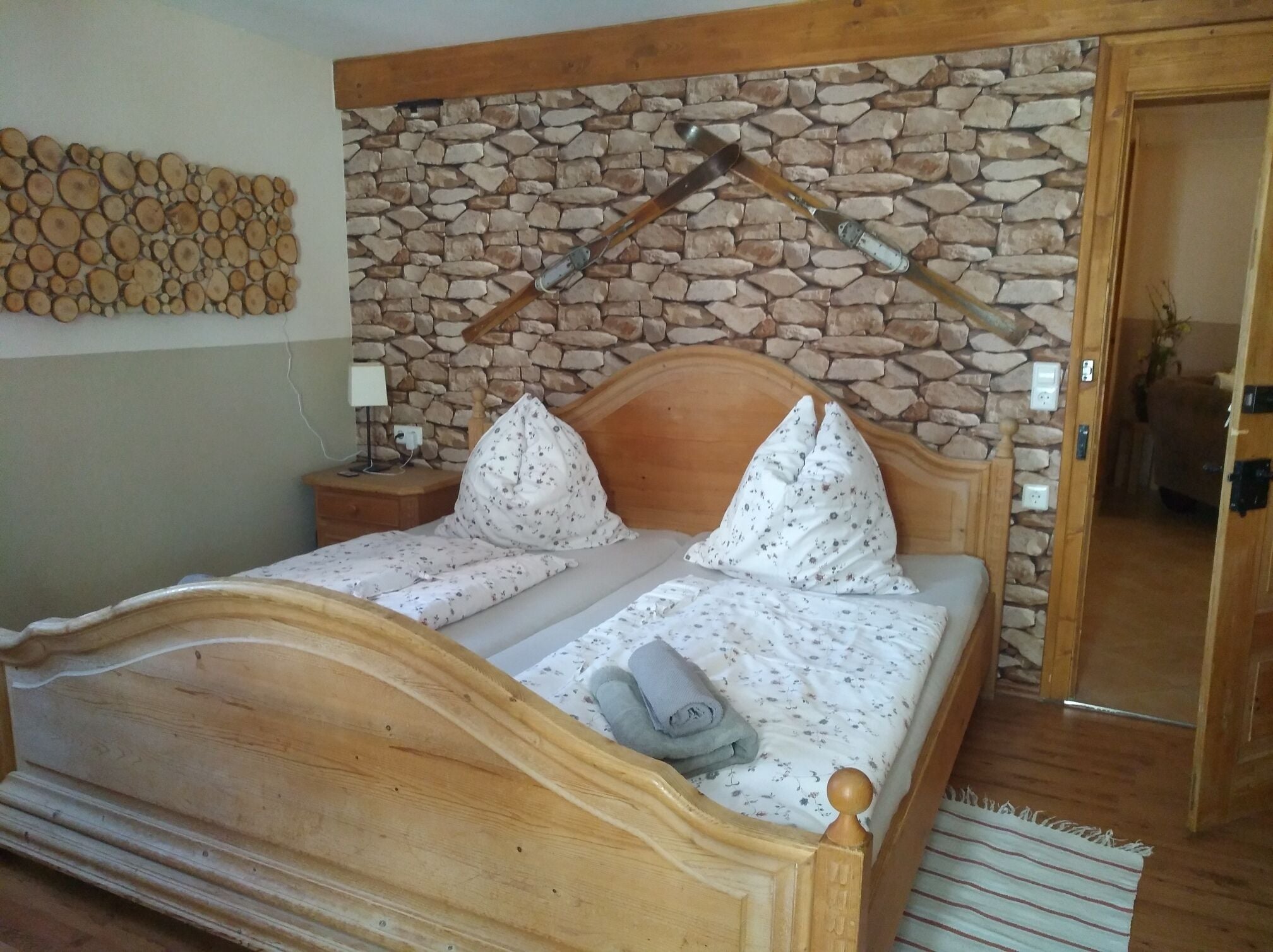 Un dormitorio con cama de madera, pared de piedra y cabecera de madera.