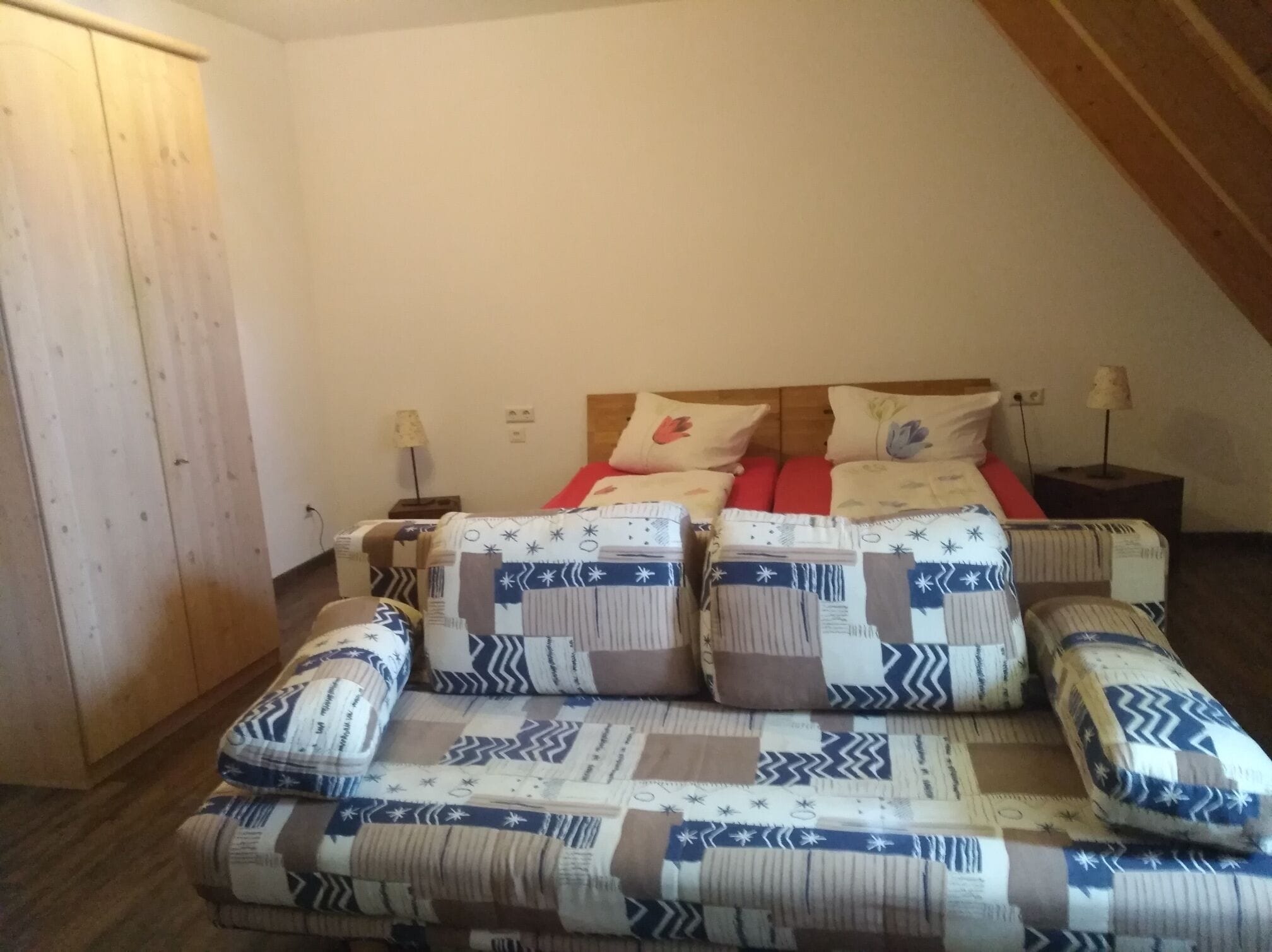 A bedroom with a bed, two bedside tables, and a wooden wardrobe.