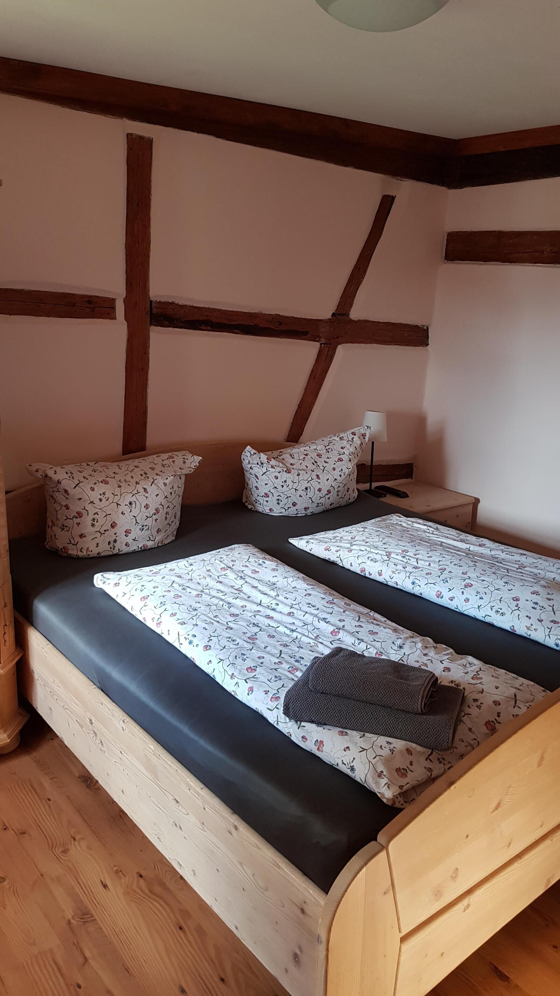 A room with two wooden beds, each with floral-patterned bedding and pillows.