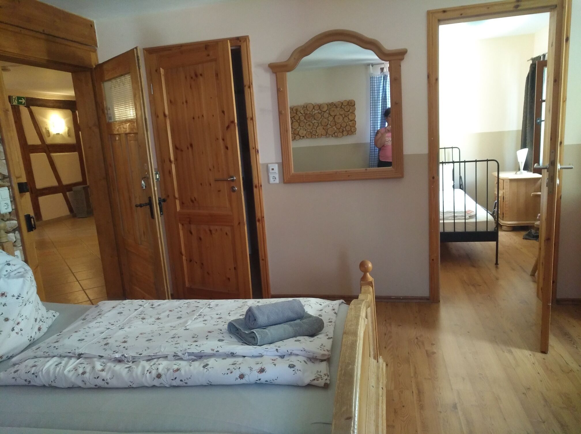 A bedroom with a wooden bed, a mirror, and a wooden wardrobe.