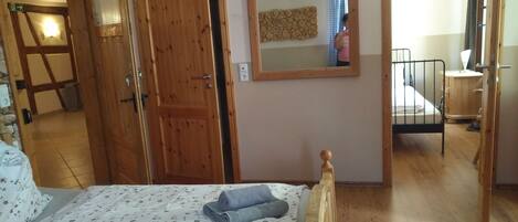 A bedroom with a wooden bed, a mirror, and a wooden wardrobe.