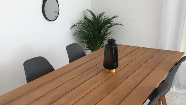 A wooden dining table with chairs, a black vase, and a potted plant in a room with white walls and tiled flooring. - Housing near downtown (Montpellier)