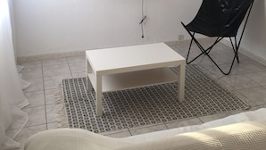 A small, sparsely furnished room with a white table, a black folding chair, and a flat-screen TV mounted on the wall. - Housing near downtown (Montpellier)