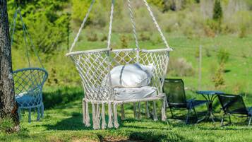 A hammock chair with white cushions in a grassy outdoor area.