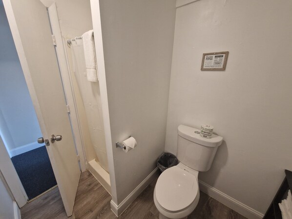 Une salle de bain avec des toilettes, une serviette accrochée au mur et une poubelle.
