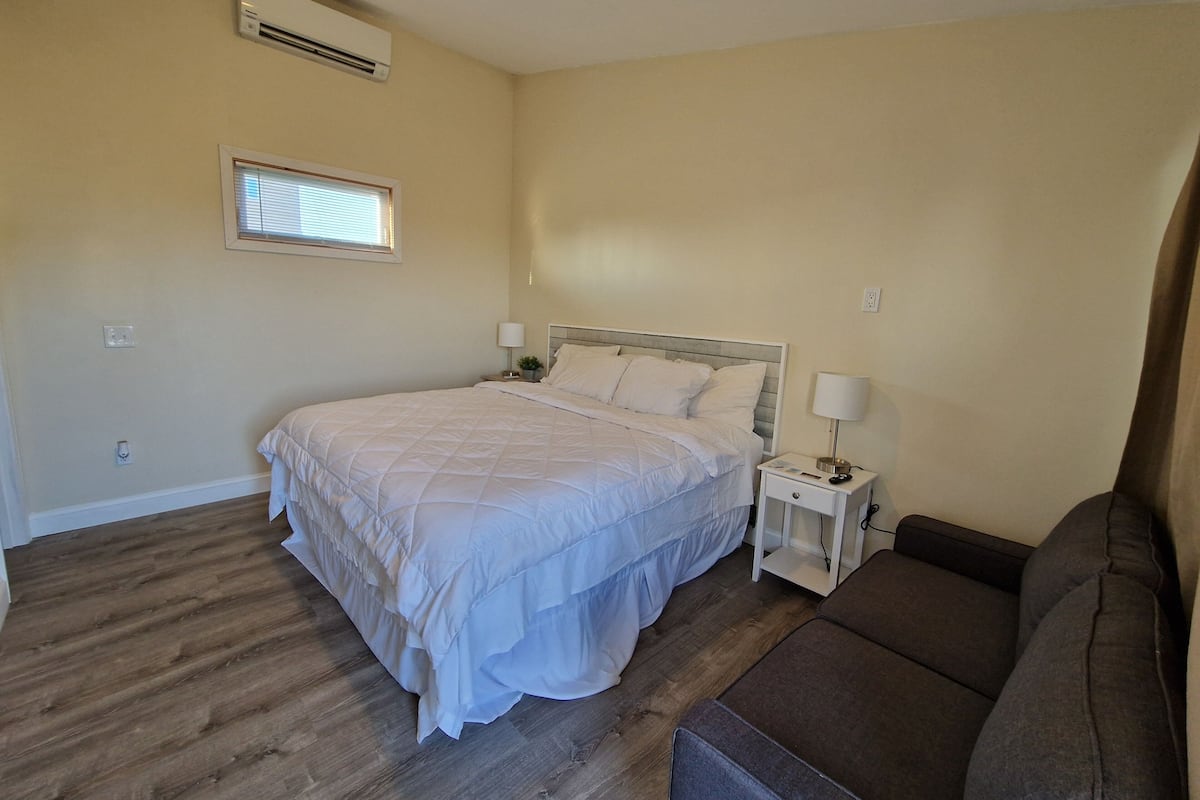 A bedroom with a bed, bedside tables, a lamp, a window, and a sofa.