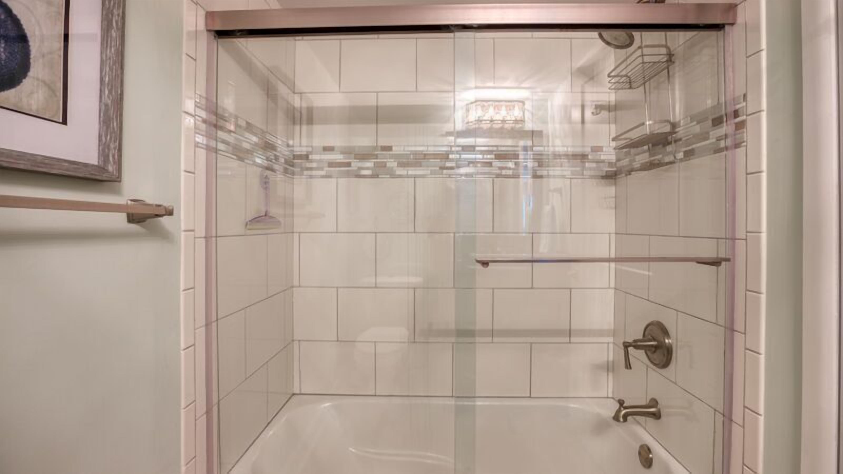 Una ducha moderna con puertas de vidrio transparente, paredes de azulejos blancos y un diseño minimalista.