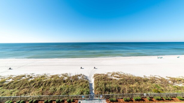 A beach with a clear sky, a sandy shore, and a pathway leading to the beach.