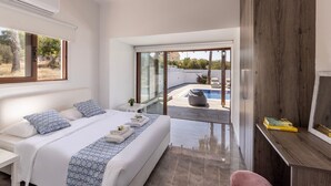 A modern bedroom with a large bed, a TV, and a view of a swimming pool.