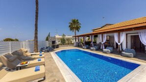 A swimming pool with lounge chairs and a covered seating area.