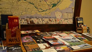 Un tavolo con diversi libri e brochure, una mappa della città di Cuenca e un cartello per 'Mapas Cafe'.