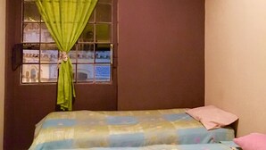 Una camera da letto con un letto, una finestra con tende e vista su un edificio.