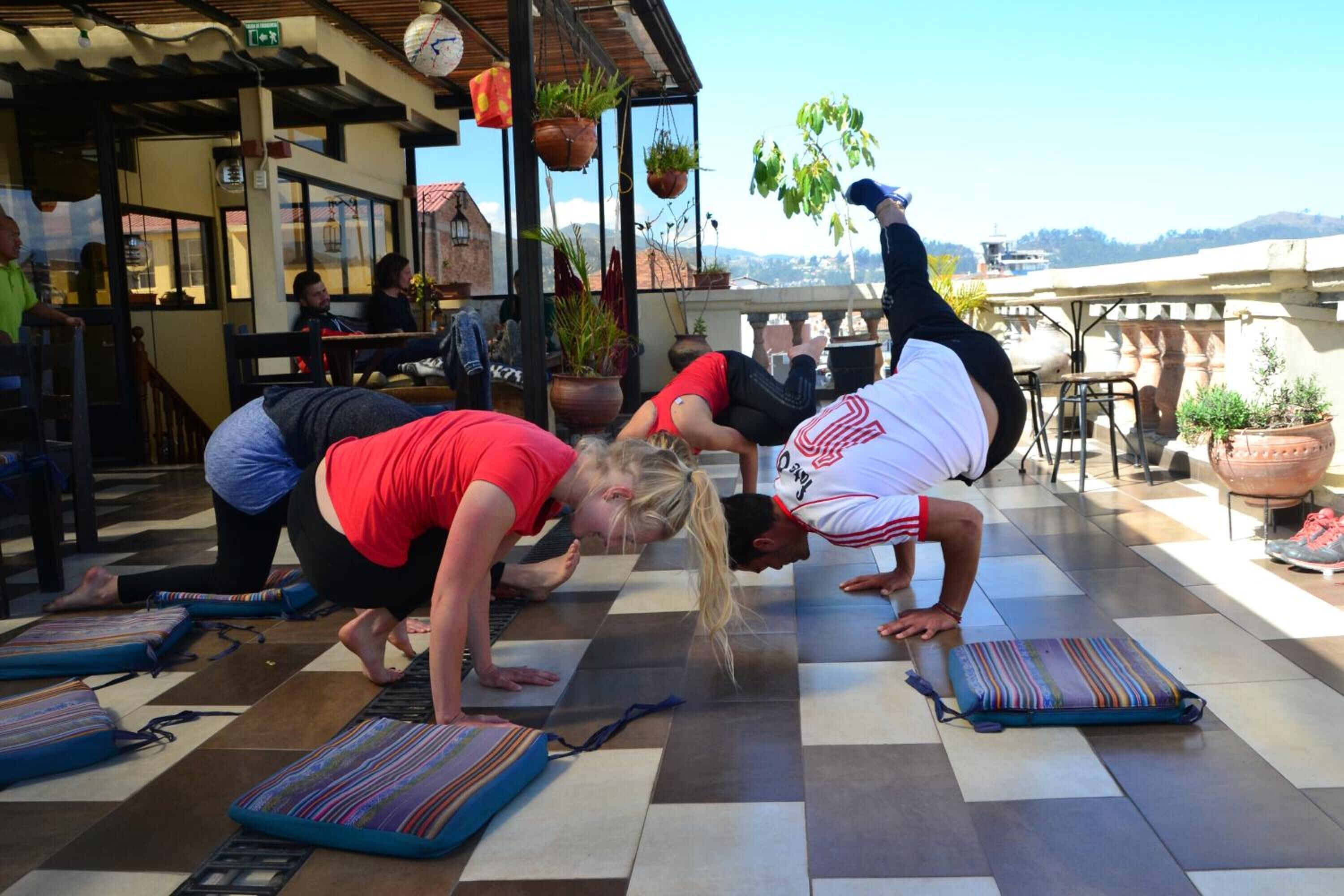 A yoga session on a checkered floor with mats, in a room with a view of the hills.
