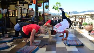 A yoga session on a checkered floor with mats, in a room with a view of the hills.