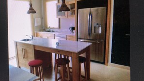 Une petite cuisine avec un évier, des tabourets et un miroir.