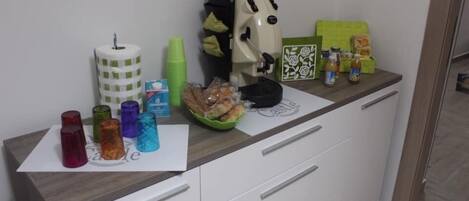 A kitchen counter with a coffee maker, a bowl of bread, and various containers.