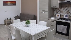 Una cocina moderna con armarios blancos, una mesa de comedor con mantel de lunares y una pequeña planta en maceta.