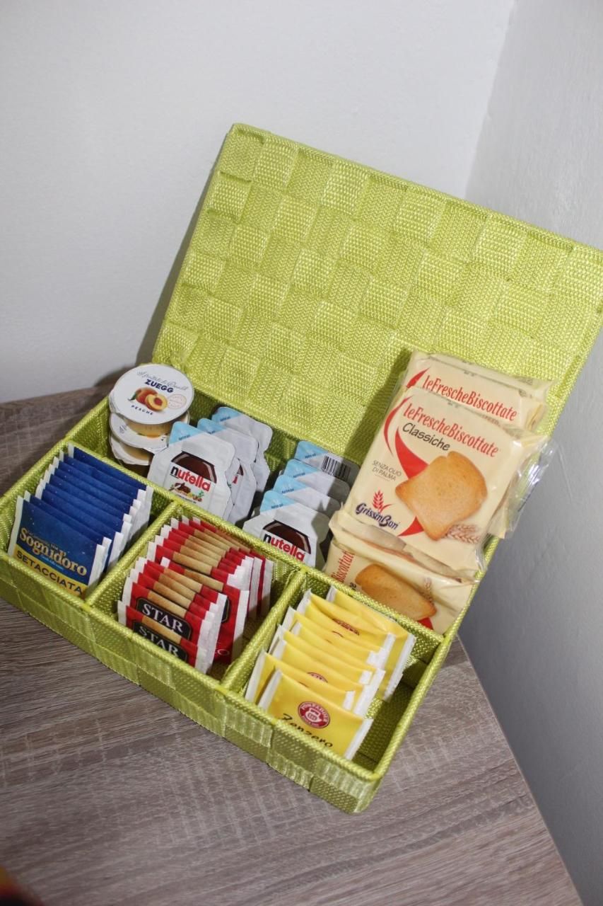 Una cesta verde con varios alimentos, entre ellos Nutella, galletas y queso.