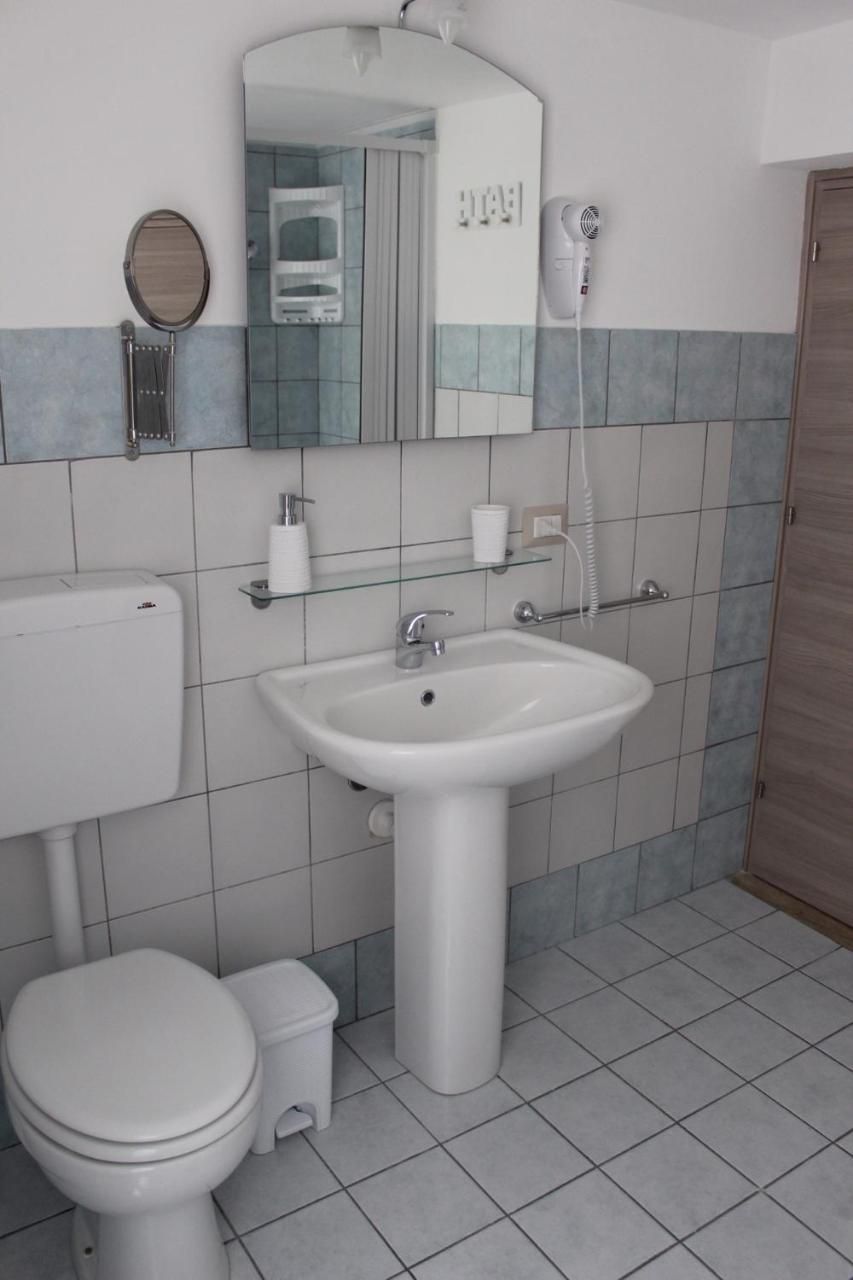 A bathroom with a toilet, sink, mirror, and hairdryer.