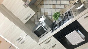 Una cocina moderna con microondas, estufa y lavabo. Hay una planta pequeña en la encimera y una toalla blanca sobre el horno.