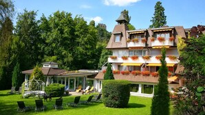 Un immeuble à plusieurs étages doté de balcons, un jardin avec des chaises et un belvédère.