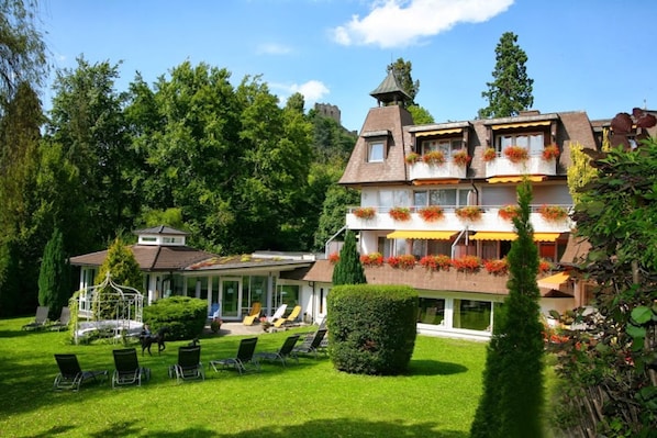 A multi-story building with a garden, outdoor seating, and a gazebo.